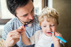 Father brushing his teeth with a toddler